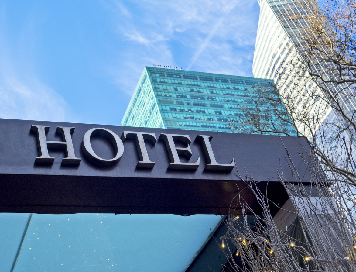 Hotel entrance sign on building with city skyline behind