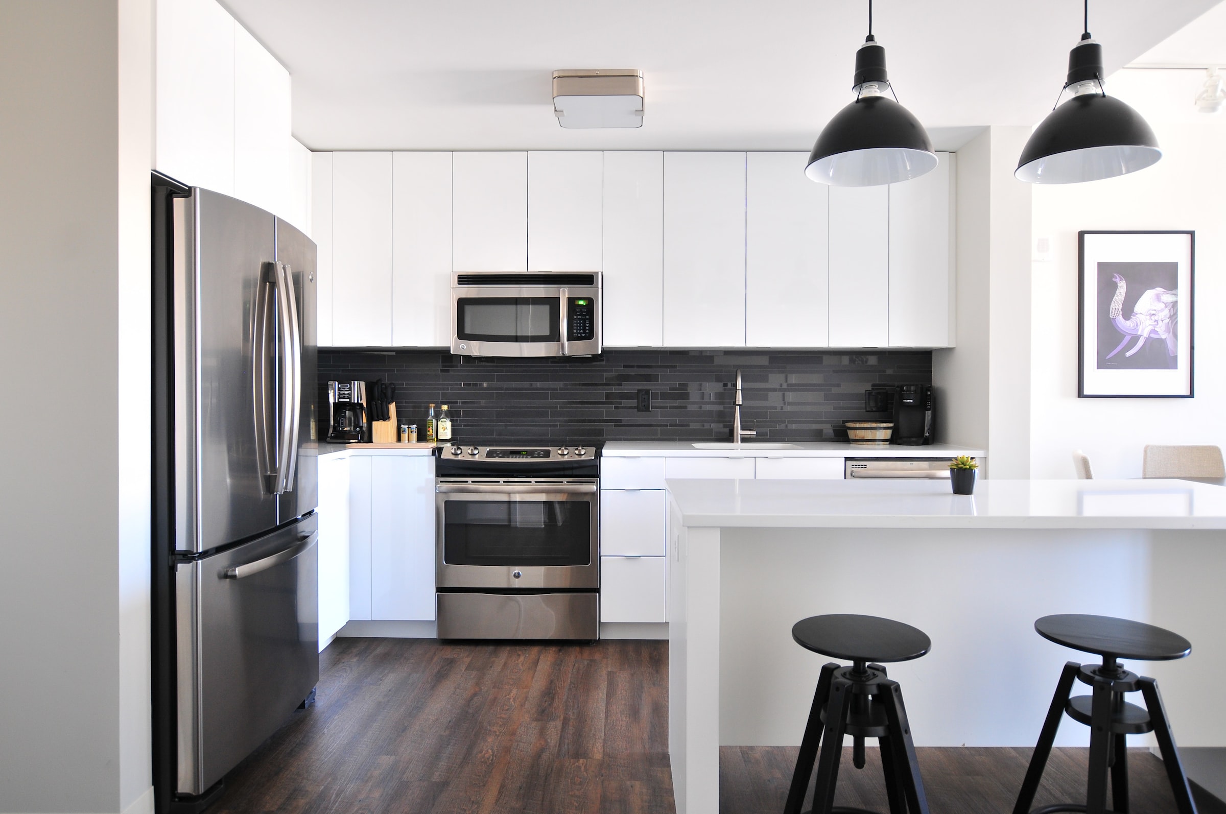 Multifamily apartment kitchen remodel with white cabinets, black pendants and stainless appliances